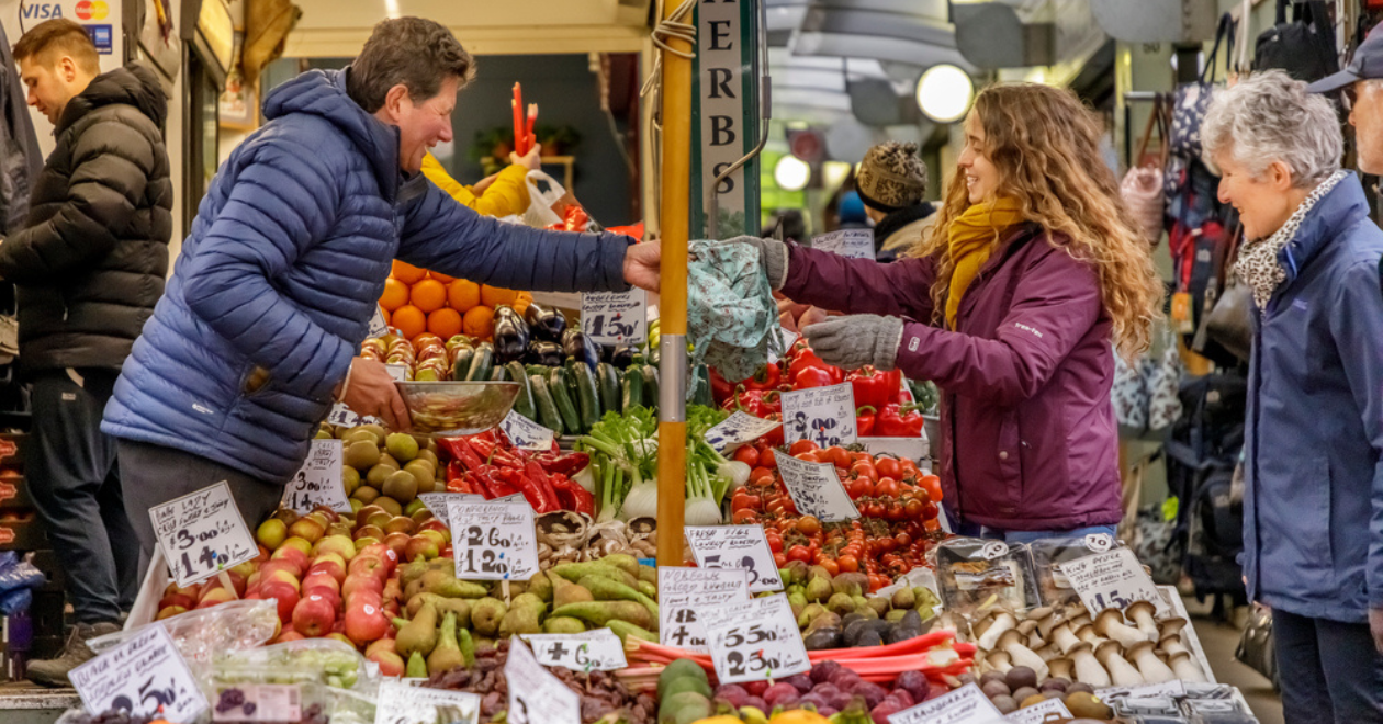 People browsing outdoor fruit and vegetable stands