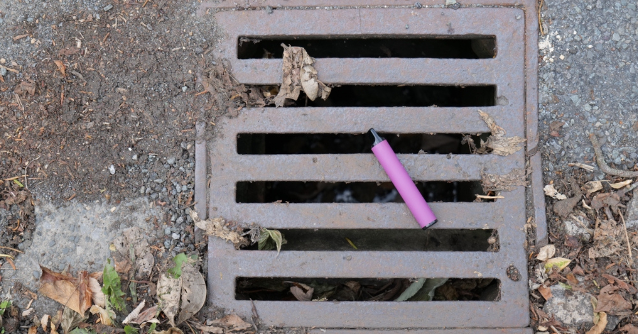 A purple e-cigarette vape has been discarded and left lying on a metal water drain cover. Credit: Shutterstock/B..Robinson