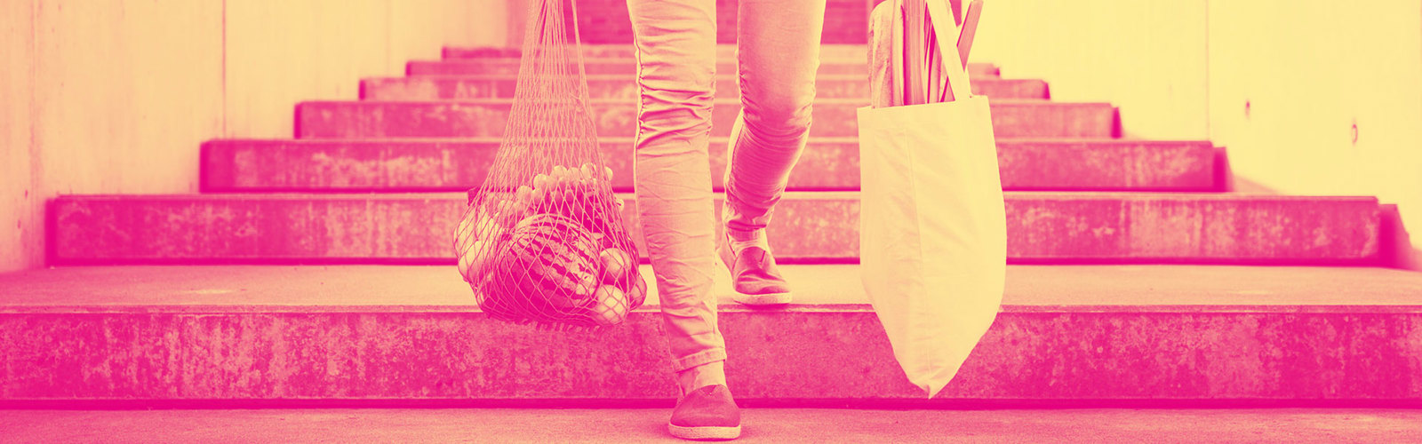 Person carrying tote bags filled with fruit and vegetables