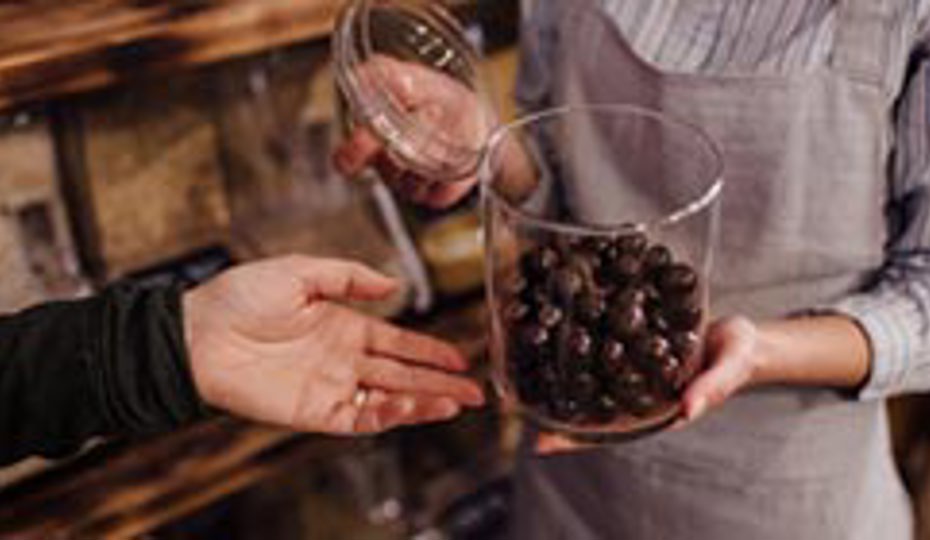 Venue assistant opens a refillable jar offering snacks to a visitor