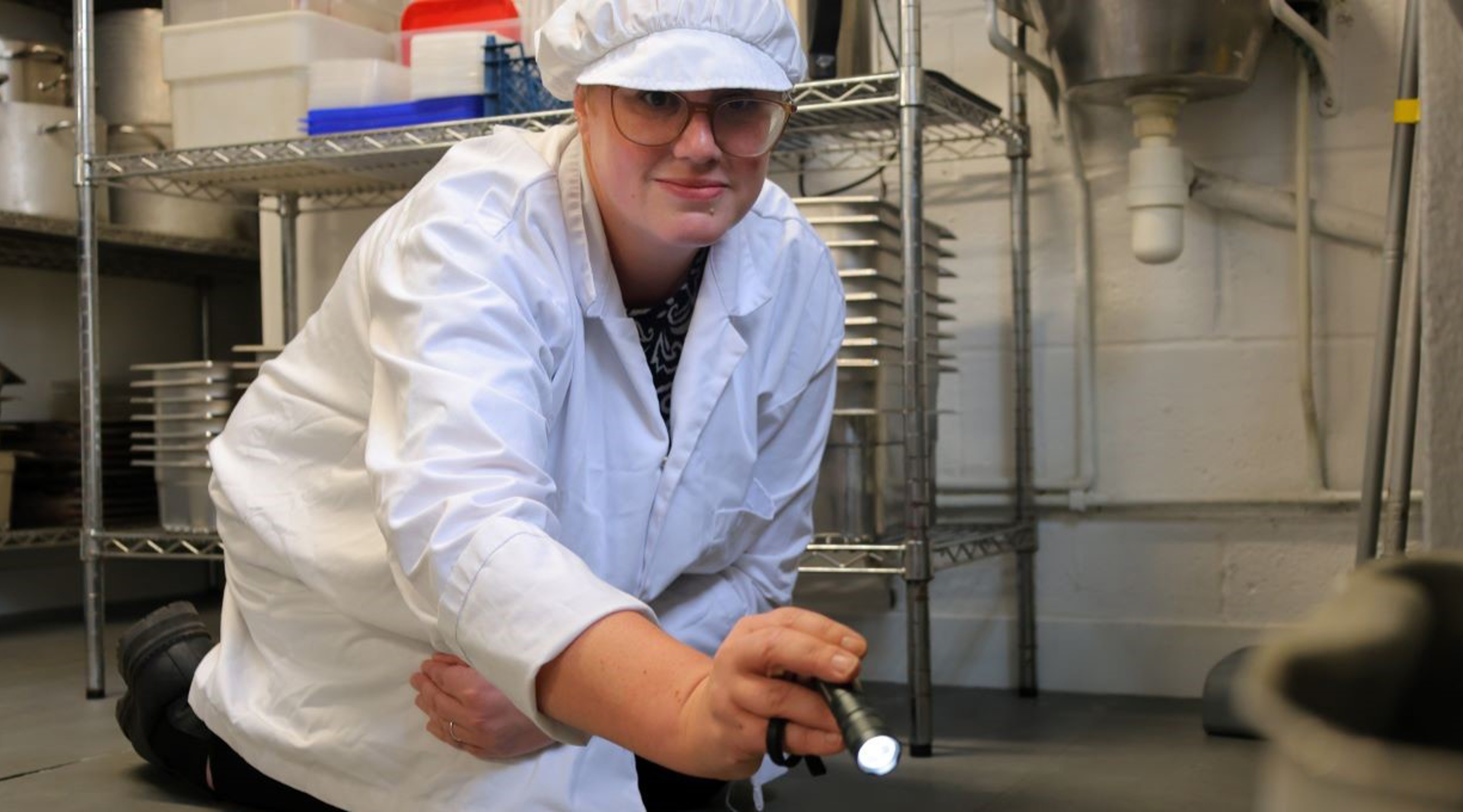 Naomi Shipman, Environmental Health Officer, holding a torch while carrying out a food hygiene inspection