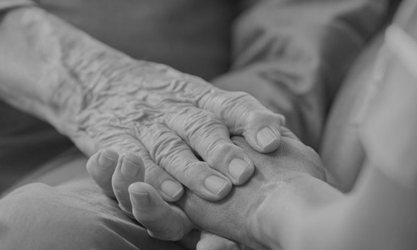 Care worker in uniform holding the hands of a resident