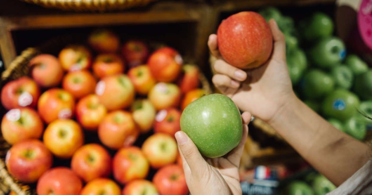 Person comparing fresh apples, tub of apples in the background