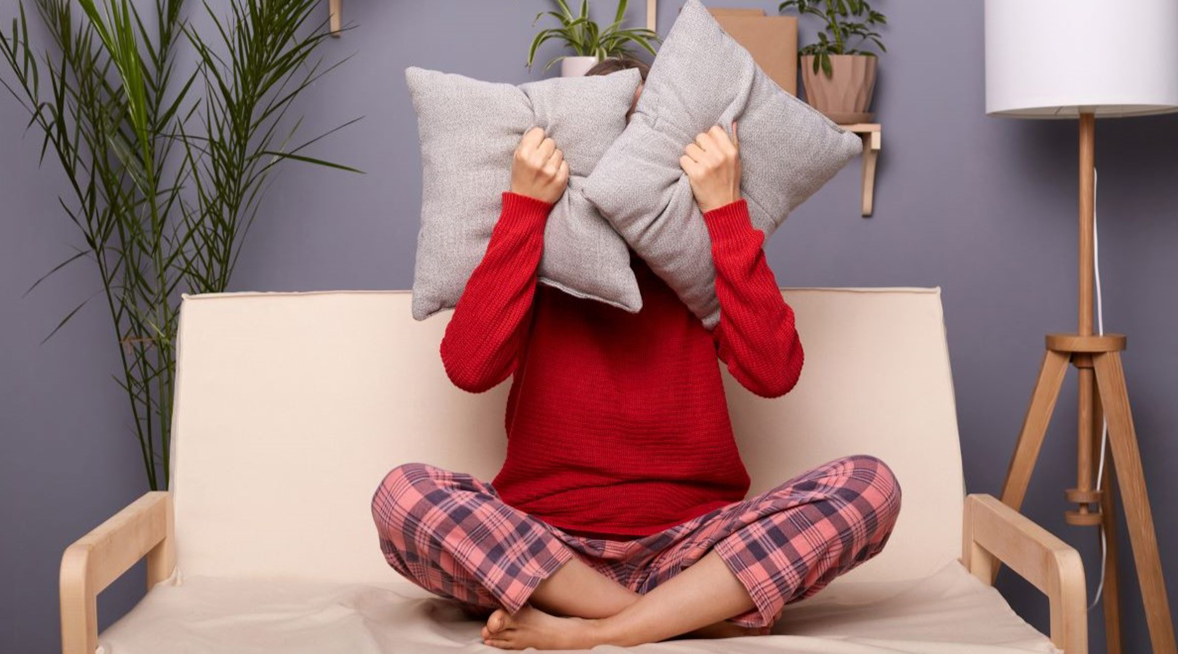 Woman sat on sofa with her head between two pillows