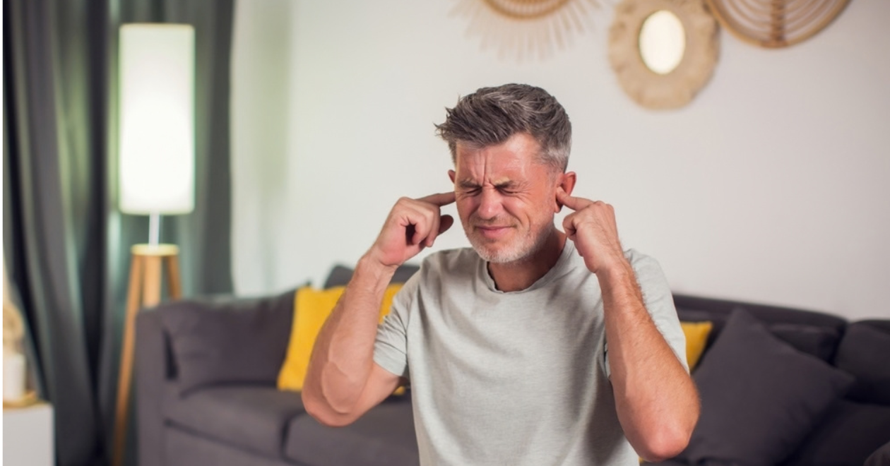 Man putting his fingers in his ears to block out noise
