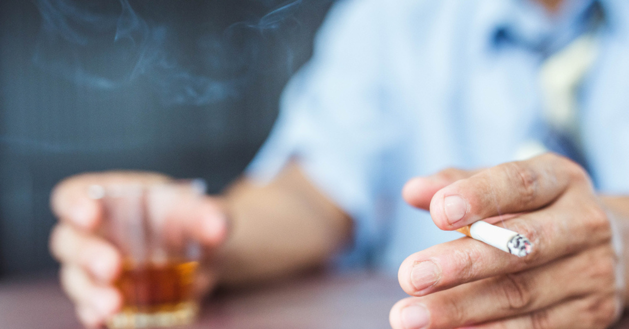 Hand drinking glass of alcohol and smoking cigarette